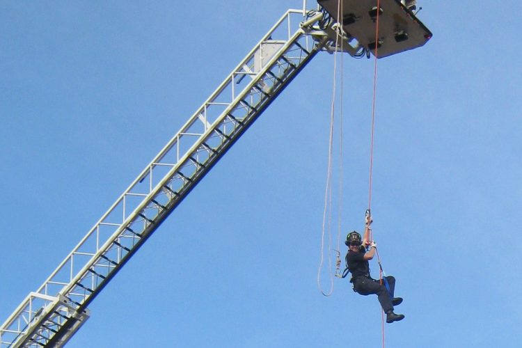 Firefighter going down the crane using rope