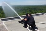 Firefighters using hose at the top of a building Thumbnail